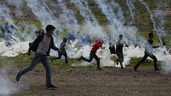 Palestinian demonstrators run away from tear gas fired by Israeli troops during a protest against Jewish settlements, in al-Mughayyir village near Ramallah, in the Israeli-occupied West Bank, on February 1, 2019.(AFP)