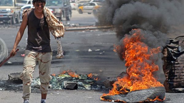 A Yemeni man walks past burning tires in Aden on Sept. 6. (Saleh al-Obeidi/AFP) 