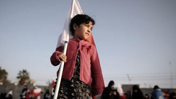 A young Bahraini girl holds a national flag during an anti-government rally in the village of Diraz, west of Manama, on January 17, 2014. [AFP]