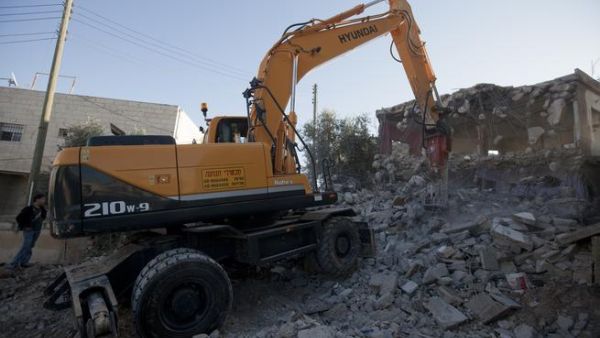 Rafet Dabash (not pictured), a Palestinian from the east Jerusalem district of Sur Baher, has his house destroyed by a bulldozer. (AFP PHOTO / AHMAD GHARABLI)