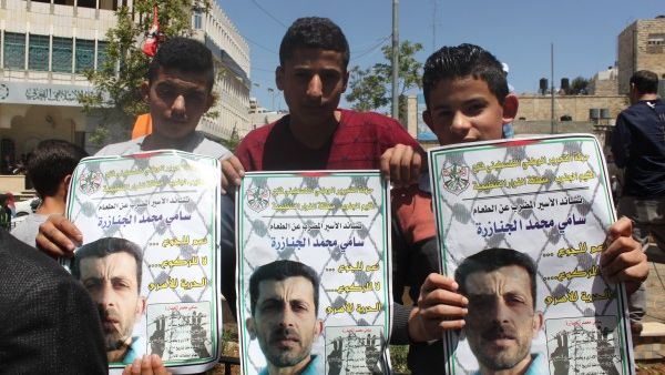 Three young demonstrators hold images of Sami Janazreh. (Palsolidarity.org)