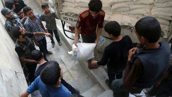 Syrians offload aid after a convoy of Syrian Arab Red Crescent and UN vehicles arrived in a rebel-held area on the outskirts of Damascus. (AFP/Amer Almohibany)