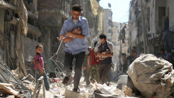 Syrian men carrying babies make their way through the rubble of destroyed buildings following a reported airstrike in Aleppo, Syria. (AFP/File)