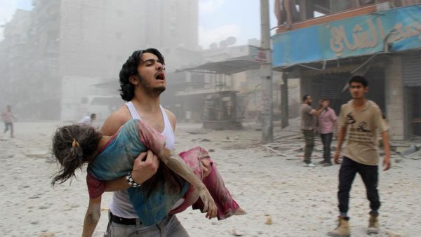 A man carries a young girl who was injured in a reported barrel-bomb attack by government forces on June 3 in Kallaseh district in the northern city of Aleppo, Syria. (AFP/File)