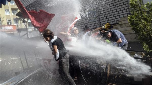 Protesters try to protect themselves as Turkish anti-riot police fire water cannon to disperse crowd. (AFP/File)