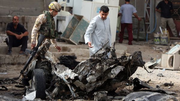 Iraqi soldiers inspect the wreckage of a car following an explosion. (AFP/File)