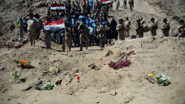 Iraqi soldiers stand next to a mass grave in Tikrmt. (AFP/File)