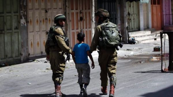 Israeli soldiers arrest a young Palestinian boy following clashes in the center of the West Bank town of Hebron, on June 20, 2014. (AFP/File)