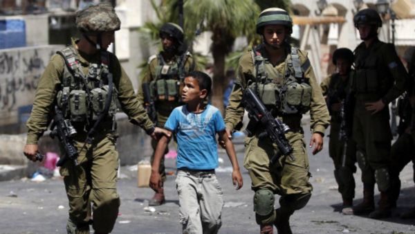 Israeli forces detain a Palestinian boy following clashes in the centre of the West Bank city of Hebron, on June 20, 2014. (AFP/File)