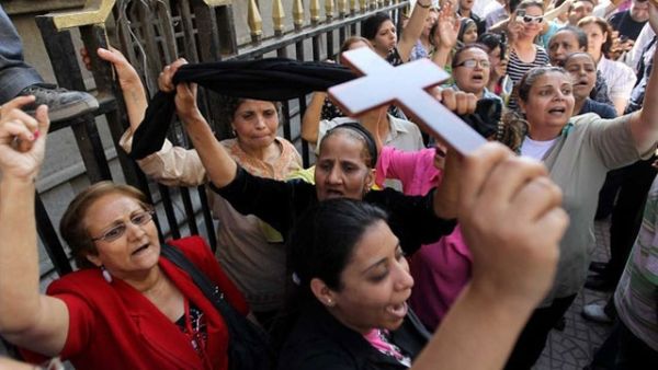 An Egyptian Coptic Christian raises a cross while others shout slogans in a demonstration last year. (AFP/File)