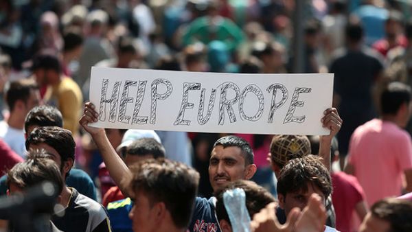 Man holds a placard reading "Help Europe" as Syrian and Afghan refugees attend a protest to demand to travel to Germany on September 2, 2015 in Budapest. (AFP/File) 