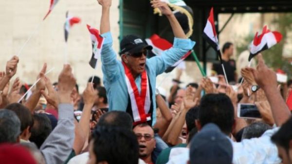 An Iraqi man chants slogans as other wave their national flag during a demonstration against corruption. (AFP/File) An Iraqi man chants slogans as other wave their national flag during a demonstration against corruption. (AFP/File)