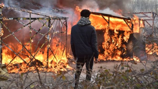 A refugee looks at shacks burning during the dismantling of half of the Jungle in Calais, France. (AFP/File)