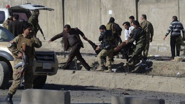 Afghan security personnels carry a victim at the site of a suicide car bomb next to a police base in Kabul on Feb 1, 2016. (AFP/Shah Marai)