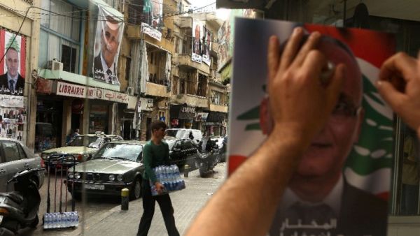 A Lebanese man puts up a poster of a candidate in the Beirut municipal elections. (AFP/File)