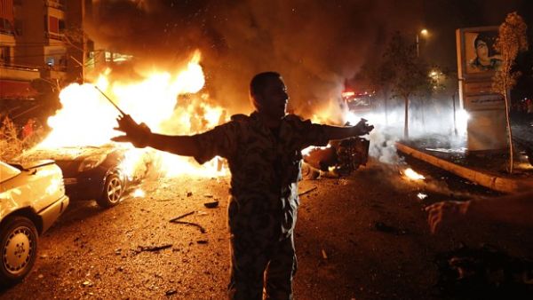 A security officer tries to keep people back as fire takes over cars at the site of a car bomb attack in Beirut. (AFP/File)