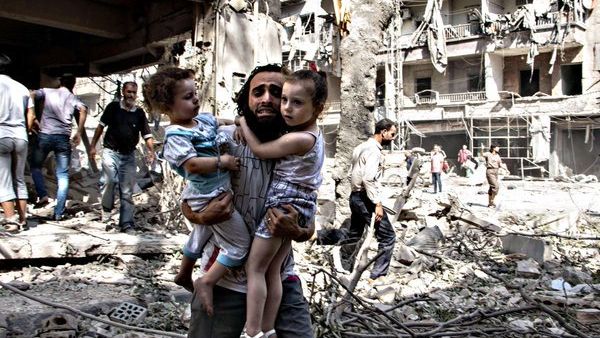 A Syrian man carries two girls as he walks across the rubble following a bombing in Aleppo. (AFP/Karam al-Masri)