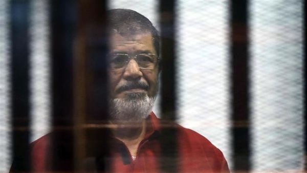 Egypt's ousted President Mohamed Morsi, wearing a red uniform, stands behind bars during his trial. (AFP/File)