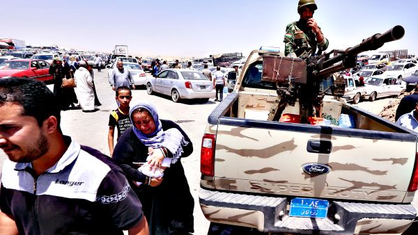 Iraqi families fleeing violence in the northern Nineveh province gather at a Kurdish checkpoint in Aski kalak, 40 km west of Erbil. (AFP/Safin Hamed)