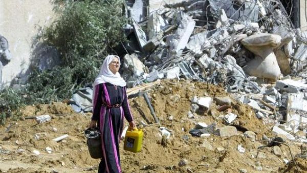 A Palestinian woman leaves what once was her home carrying a gas cooker after her house was bulldozed by the Israeli Army, a practice Human Rights Watch says could be war crime. (AFP/Said Khatib)