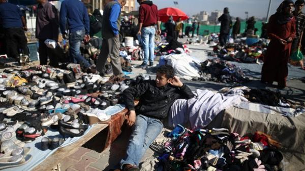 A Palestinian boy sits amidst used clothes and items at the weekly flea market in the Nusseirat Refugee Camp, central Gaza Strip, on February 29. (AFP/File)