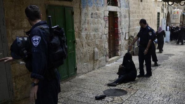 A Palestinian woman is blocked from entering the al-Aqsa Mosque compound, sits on the ground during a tension moment between Israeli security forces. (AFP/File)