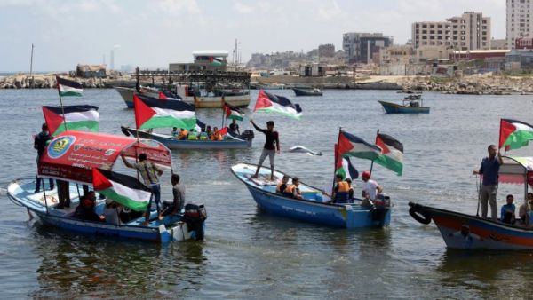 Palestinians hold their national flag as they ride boats during a rally to show support for activists aboard the flotilla. (AFP/Mahmud Hams)
