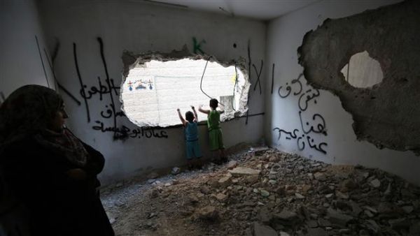 Palestinians stand at a house that was demolished by Israeli authorities in the Qalandia refugee camp. (AFP/File) Palestinians stand at a house that was demolished by Israeli authorities in the Qalandia refugee camp. (AFP/File)
