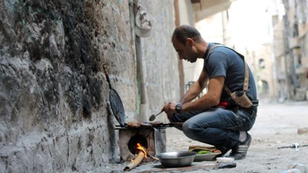 A rebel fighter cooks food on a make-shift stove in Syria's Aleppo. (AFP/File)