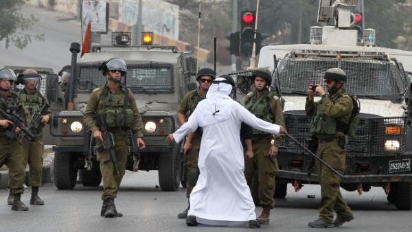 An elderly Palestinian man acts as a human barrier between Israeli security forces and Palestinian stone throwers during clashes following Friday prayers in the West Bank town of Hebron. (AFP/File)