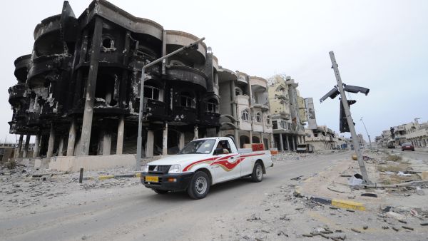 Libyans drive through a destroyed neighborhood in Sirte in 2011. (AFP/File)
