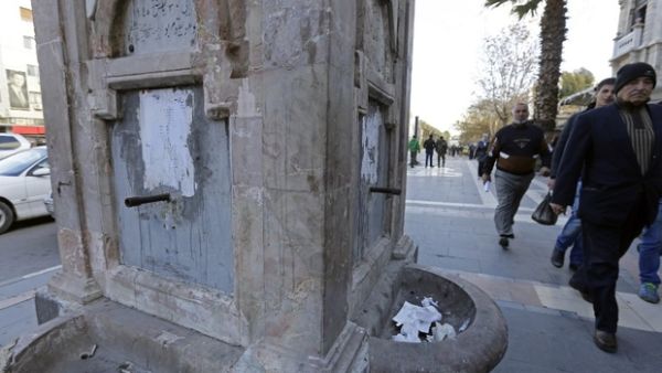 Syrians walk past a water fountain that is running dry as shortages leave over 5 million people with little to no running water. (AFP/File)