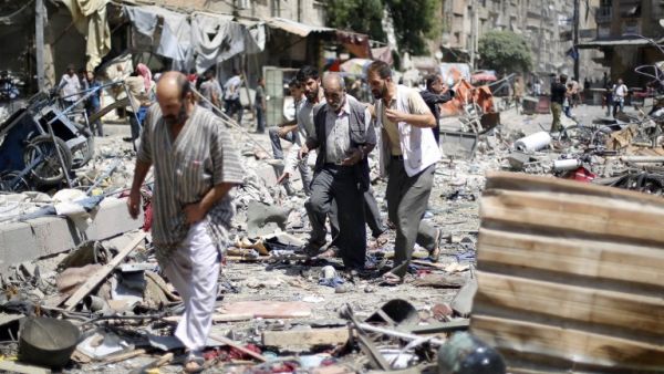 Syrians walk amid the rubble following air strikes by Syrian government forces on a marketplace. (AFP/File)