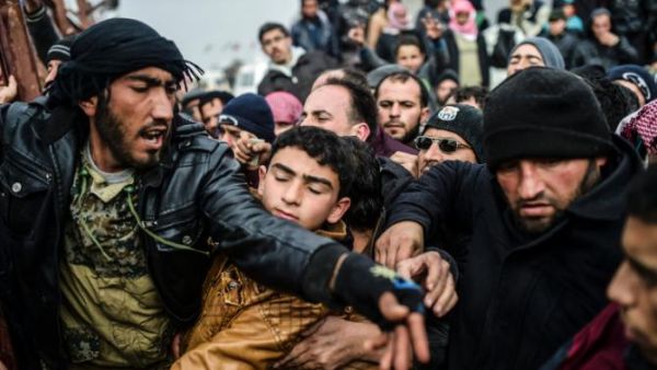 Syrian refugees jostle each other near the Turkish border crossing on February 6, 2016. (AFP/File)