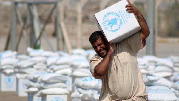 A displaced Iraqi collects boxes of food donated by the World Food Program. (AFP/File)