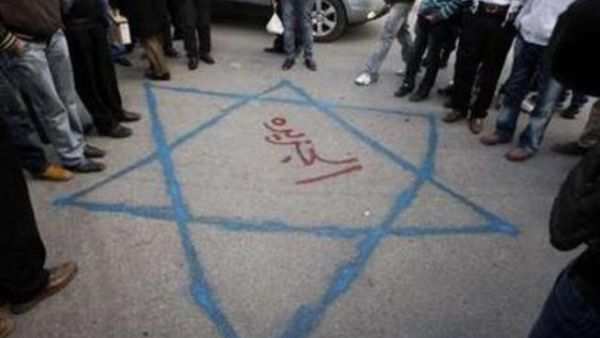 فلسطينيون في رام الله يتحلقون حول رسم على الارض لعلم اسرائيلي كتب في وسطه اسم قناة الجزيرة