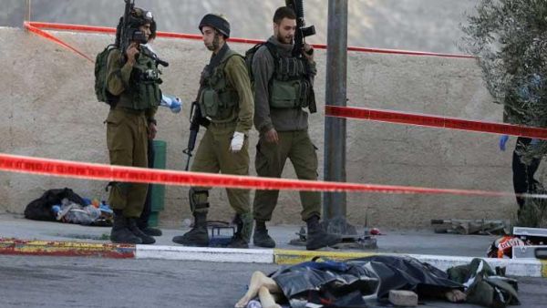 شهيد فلسطيني ملقى على الارض بجانب جنود الاحتلال/ ارشيفية