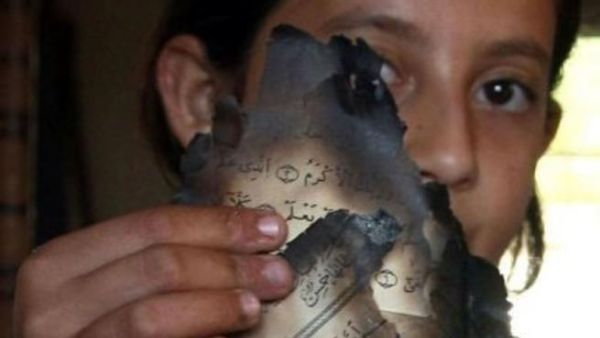 ليندا بيدا تحمل صفحات من المصحف بعد احراقه في منزل والديها في قرية جيوس في شمال الضفة الغربية
