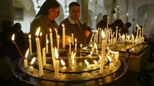 شخصان يوقدان الشموع في كنيسة المهد في بيت لحم

