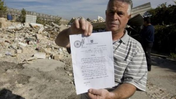 الفلسطيني عزيز زبلح يعرض حكما بوقف قرار تدمير منزله امام ركام المنزل في حي الطور