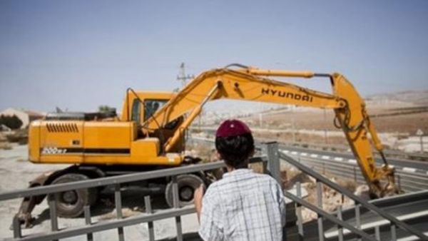 صبي من المستوطنين يراقب الية حفر في احد المواقع الاستيطانية