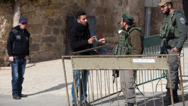 A Palestinian man has his identity checked by Israeli border police patrolling the streets of the West Bank city of Hebron on January 5, 2016. (AFP/Menahem Kahana)