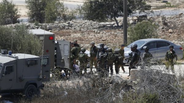 Israeli soldiers surround the body of a suspected Palestinian man who was reportedly shot dead by Israeli troops at the entrance to the West Bank village of Silwad on August 26, 2016. (AFP/Abbas Momani)