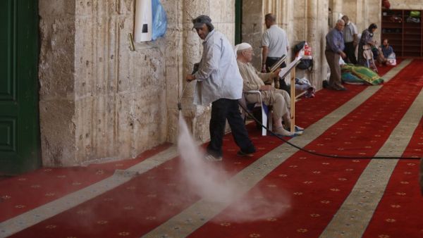 A Palestinian man clears the damage at the entrance of Al-Aqsa Mosque in Jerusalem's Old City after clashes erupted at the compound between Palestinians and Israeli police on June 26, 2016 during the holy month of Ramadan. (AFP/Ahmad Gharabli)