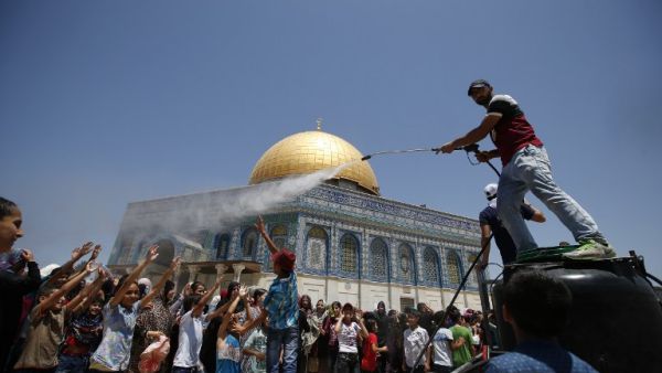 A man sprays water to cool down Palestinian children gathering in front of the Dome of the Rock in Jerusalem's Al-Aqsa mosque compound before Friday prayers during Ramadan on June 24, 2016. (AFP/Ahmad Gharabli)