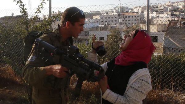 An Israeli soldier scuffles with a Palestinian woman who is trying to film the scene of a reported Palestinian stabbing attack on a soldier near the Jewish settler enclave of Tal Rumeda in the city centre of the West Bank town of Hebron on September 16, 2016. (AFP/Hazem Bader)