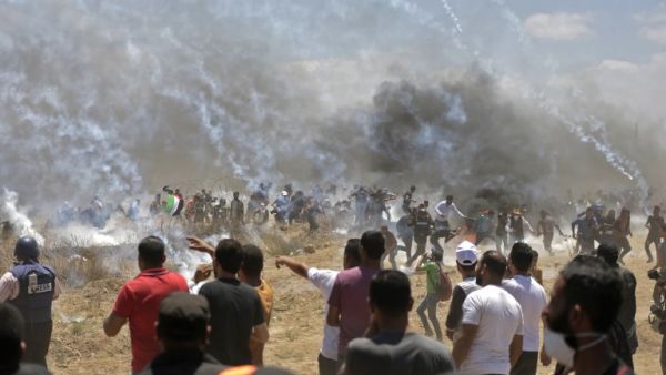 Palestinian protesters run for cover from tear gas during clashes with Israeli forces near the border between the Gaza strip and Israel east of Gaza City on May 14, 2018, as Palestinians protest over the inauguration of the US embassy following its controversial move to Jerusalem. (MAHMUD HAMS/ AFP)