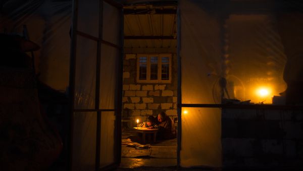 A Palestinian woman helps her son study, by candlelight, at their makeshift home in the Khan Yunis refugee camp in the southern Gaza Strip on April 19, 2017. (AFP/Mahmud Hams)