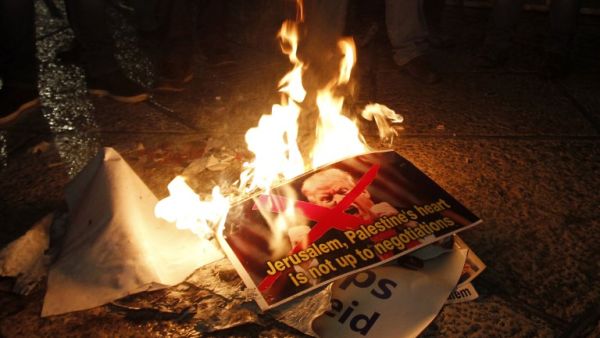 Palestinian demonstrators burn posters of the US president in Bethlehem's Manger Square in protest to him declaring Jerusalem as Israel's capital on December 6, 2017 (Musa Al Shaer/AFP)