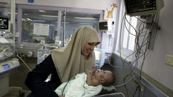 Gazan Jumana Daoud carries her 7-month-old daughter Maryam at Makassed Hospital in East Jerusalem on February 20, 2017 as they meet for the first time since the baby’s premature birth. [AFP/Ahmad Gharabli]